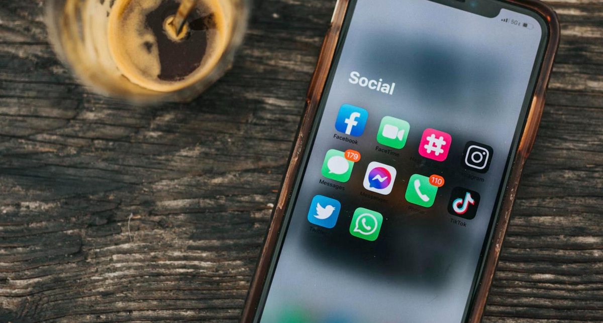 Smartphone showing social media apps beside a coffee